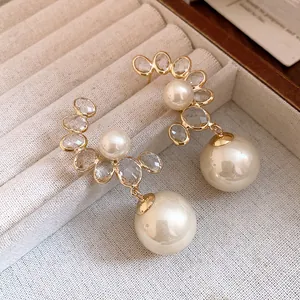 Primo piano di orecchini a pendente con perle vintage e cristalli finitura oro