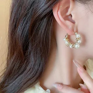 Détail en gros plan d'une boucle d'oreille créole en or 14 carats avec perle et zircon