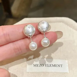 Close-up of matte silver ball earrings with pearl drops and star engravings