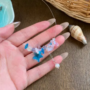 Detailaufnahme der Halskette mit blauem Seestern, Muschel-Anhänger und Perlen.
