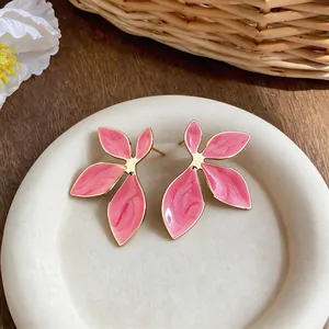 Close-up of artistic pink enamel flower stud earrings with elegant gold-tone edges.
