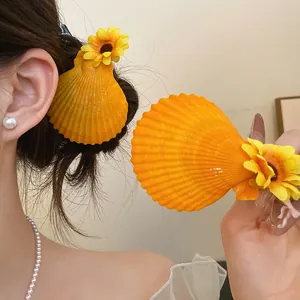 Detail view of orange scallop shell hair clip with yellow flower decoration