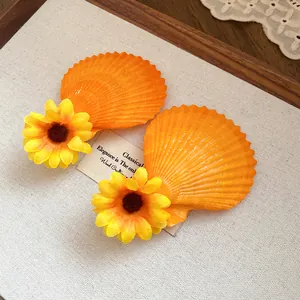 Close-up detail of resort style orange shell hair clips decorated with yellow fabric flowers