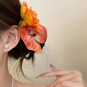 Detail view of a vibrant orange fabric orchid hair clip for elegant vacation hairstyles.