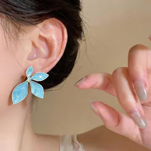 Macro detail view of elegant light blue oil-drop flower earrings with silver needles