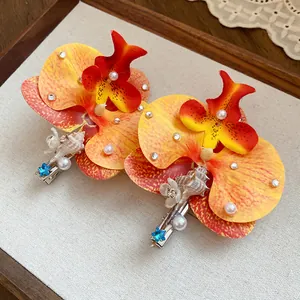 Detail view of fabric orchid hair clips with pearls, shells and crystals on a display tray.