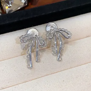 Elegant silver lace bow clip-on earrings for non-pierced ears on jewelry tray