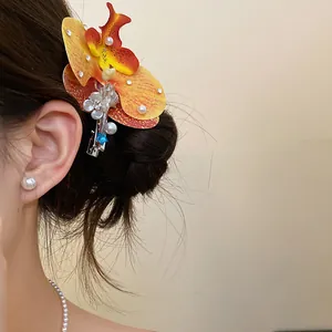 Detailed view of an orchid flower hair clip with pearls and shells on a model's hair.