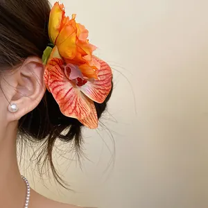 Elegant fabric orchid flower hair clip worn on the side by model for a resort look