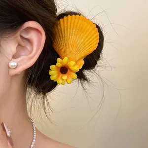 Close-up of a yellow shell hair clip with a fabric flower decoration on model's hair.