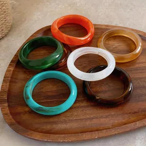Ensemble de bracelets en acrylique géométriques marbrés sur un plateau en bois