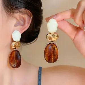 Close-up of Maillard retro resin drop earrings featuring amber and gold accents