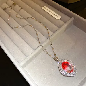 Primer plano de un lujoso collar con colgante de circón rojo en un joyero de terciopelo.