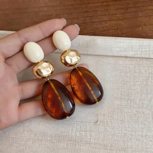 Detailed close-up of vintage Maillard resin earrings with amber drops and gold beads