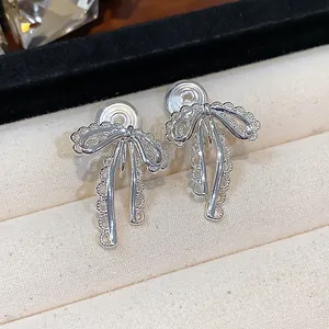 Macro view of silver lace bow-knot clip-on earrings displayed in a luxury jewelry box
