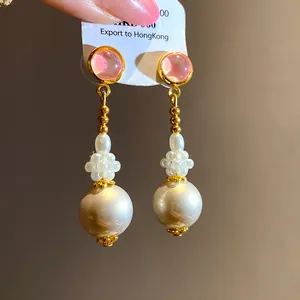 Vista dettagliata di eleganti orecchini pendenti con pietre rosa e perle bianche