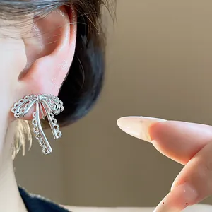 Close-up of elegant silver lace bow ear clips worn on the ear showing delicate texture.