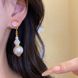 Primo piano di eleganti orecchini pendenti con perle in resina mostrati su una modella