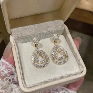 Close-up of elegant gold teardrop hollow earrings with pavé zirconia in a gift box.