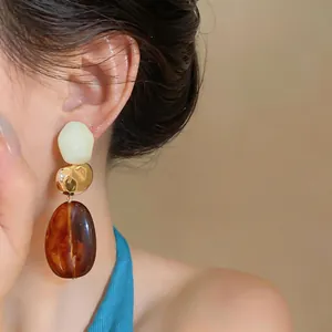 Detail shot of geometric resin drop earrings featuring retro Maillard brown amber tones