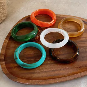 Gros plan détaillé de bracelets en acrylique marbré coloré sur un plateau en bois rustique
