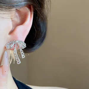 Close-up of elegant silver lace bow clip-on earring worn on a female ear for details