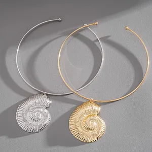 Macro view of textured gold and silver nautilus shell pendants on sleek metal choker necklaces.