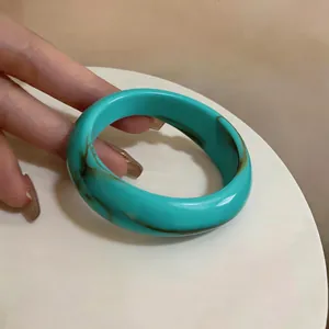 Gros plan d'un bracelet en acrylique marbré turquoise au design géométrique irrégulier unique
