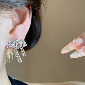 Detailed close-up of a silver lace bow ear clip worn on ear with elegant manicure