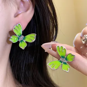 Detailed macro view of green enamel butterfly earrings with sparkling rhinestone centers
