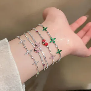 Close-up detail of five colorful zircon flower and heart charm bracelets on a woman's wrist.