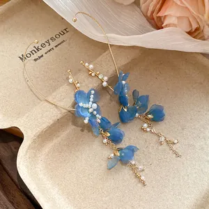 Primo piano di orecchini a nappa in chiffon blu con delicati accenti di perle
