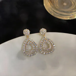 Close-up of teardrop-shaped hollow earrings with sparkling white cubic zirconia