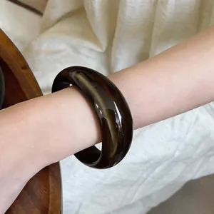 Gros plan d'un jonc en acrylique ambre foncé sur un poignet pour bijoux élégants