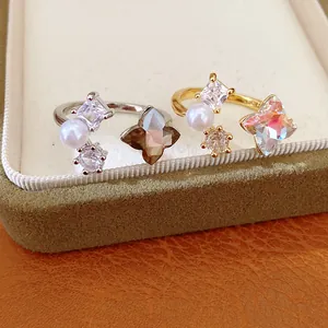 Detailed macro shot of elegant open rings with pearls, zircons, and flower crystal accents.