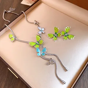 Close-up of enamel butterfly jewelry set with vibrant green and blue gradient wings.