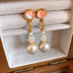 Dettaglio orecchini in argento con perni in resina rosa e pendente di perla bianca