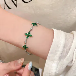 Detail shot of a silver-tone bracelet with green zircon flowers on a woman's wrist.