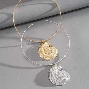 Macro detail of gold and silver metallic shell torque necklace on textured grey surface