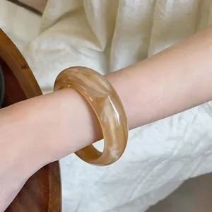 Vue détaillée du bracelet en acrylique marbré avec d'élégants motifs beiges.