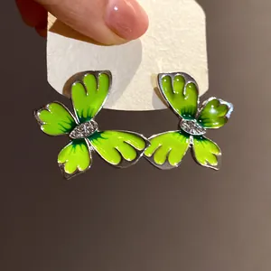 Close-up macro view of green enamel butterfly earrings with rhinestone center detail