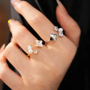 Close-up view of elegant zircon flower and pearl open rings worn on a hand for detail.
