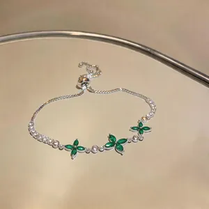 Close-up of elegant silver-toned bracelet featuring green zircon flowers and sliding clasp