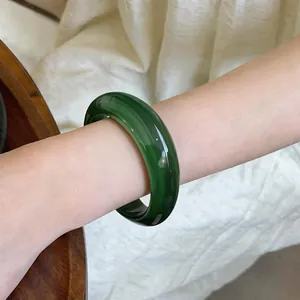 Vue détaillée d'un bracelet jonc en acrylique vert foncé avec un motif marbré sur le poignet