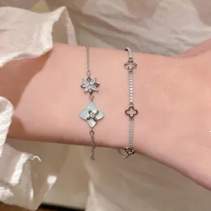 Close-up view of elegant silver zircon flower and four-leaf clover motif bracelets on wrist