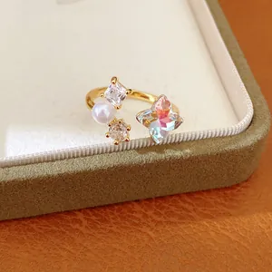 Close-up detail of gold-tone open ring with iridescent flower crystal and pearl accent.