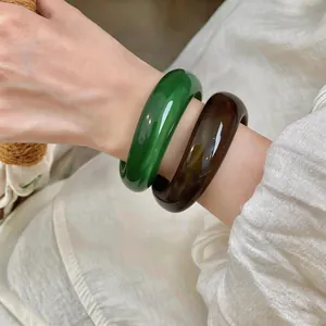 Détail de gros plan de bracelets en acrylique vert émeraude et marron marbré au poignet