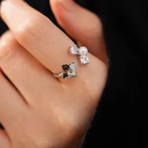Close-up detail of silver open ring featuring a grey zircon flower and white pearl