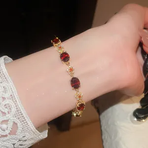 Close-up of 18k gold plated bracelet with red oval zircons and flower motifs