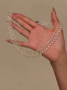 Detailed view of a vintage pearl beaded lace necklace held by hand for elegant display.